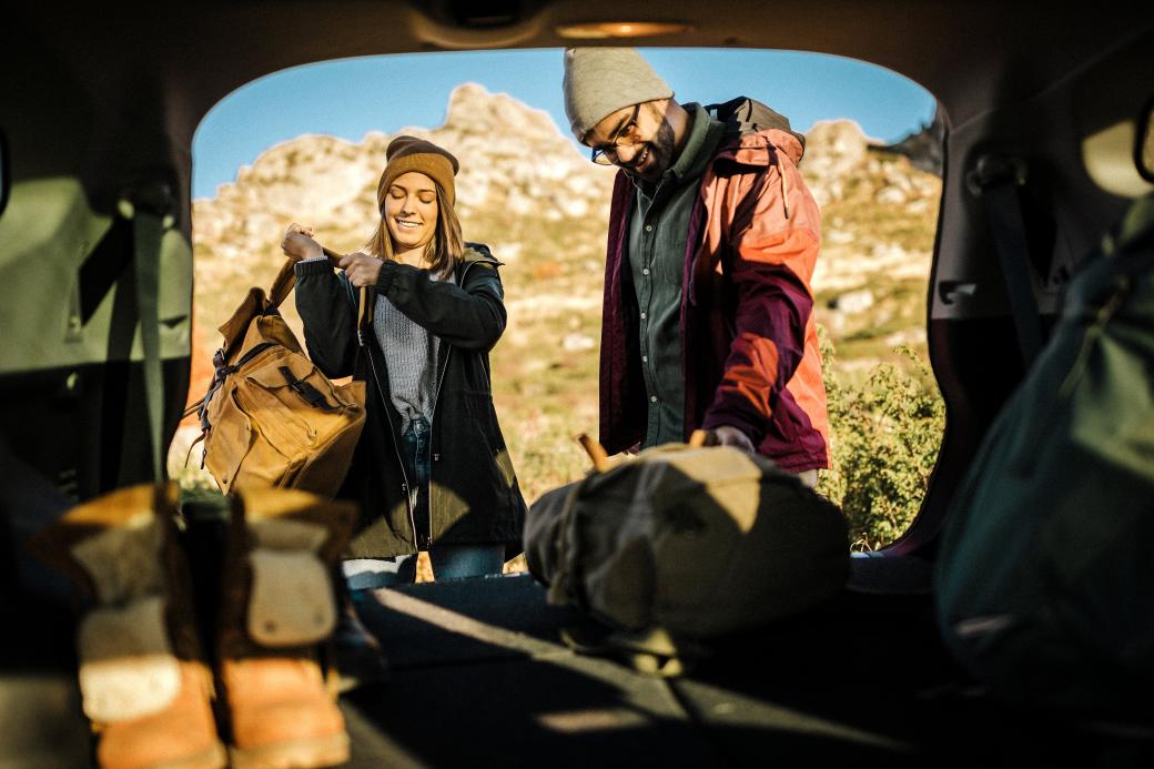 Two people unloading a car for a camping trip