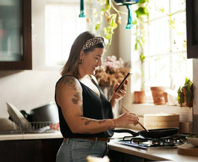 Female reading phone while cooking